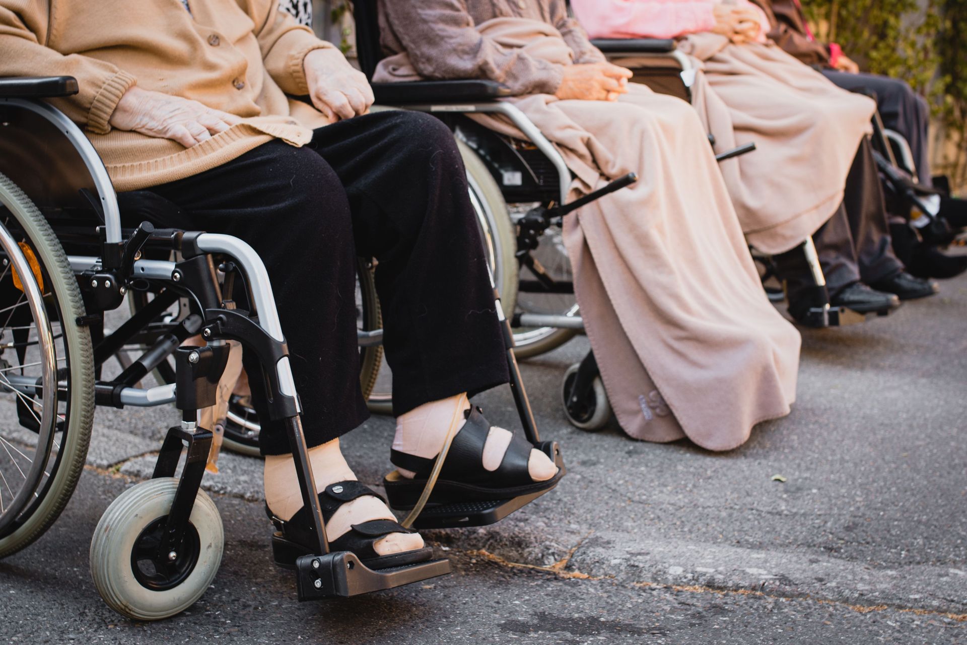 Senior adults sitting in wheelchairs outdoors enjoying a sunny day.